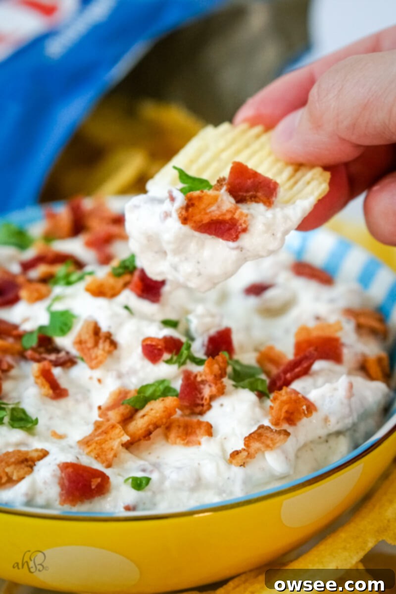 Smoky Horseradish Bacon Sensation 2 A chip scoops up bacon horseradish dip from a blue and white striped bowl.