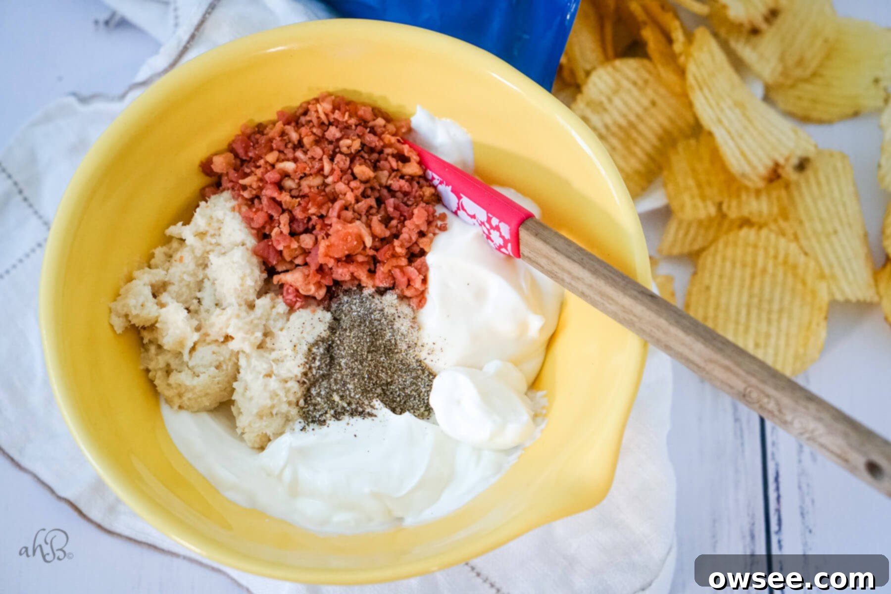 Smoky Horseradish Bacon Sensation 6 The ingredients are all added to a yellow bowl and stirred with a spatula.