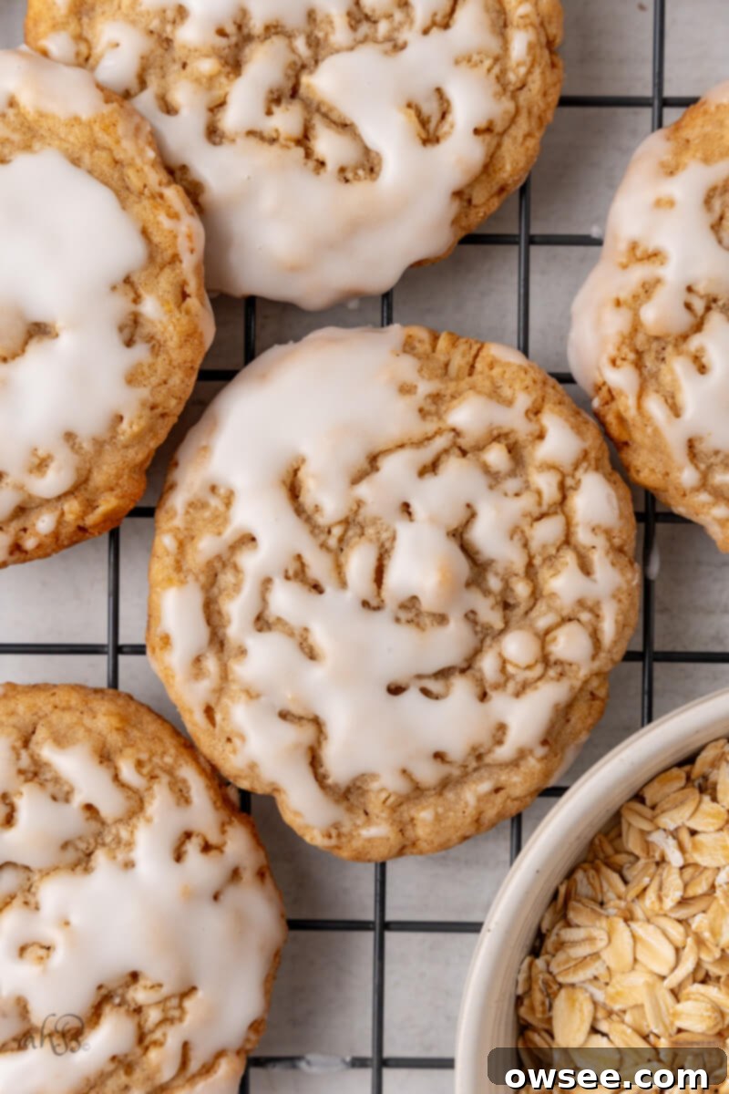 Iced Oatmeal Cookies-12 An iced oatmeal cookie sits on a cooling rack next to other cookies and a bowl of oats.