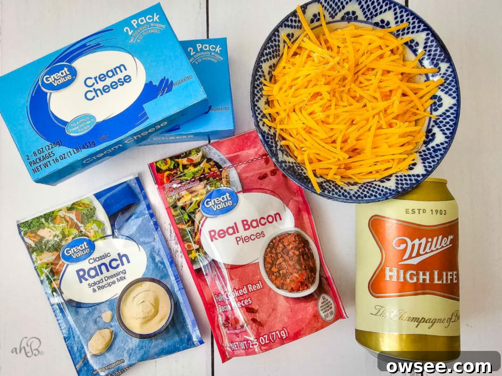 Creamy Ranch Beer Cheese Dip 5 The five essential ingredients for Ranch Beer Cheese Dip: two packages of cream cheese, a bowl of shredded sharp cheddar, a ranch seasoning packet, a package of real bacon pieces, and a can of Miller High Life beer.
