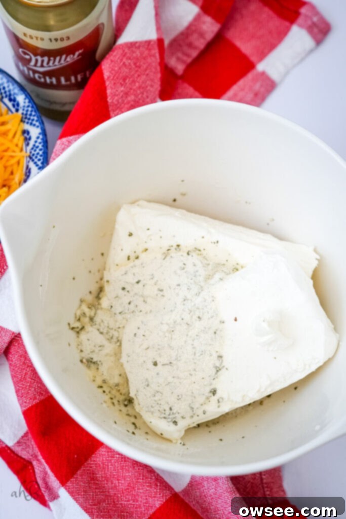 Creamy Ranch Beer Cheese Dip 6 Softened cream cheese, ranch seasoning packet, and beer are added to a mixing bowl, ready to be combined.