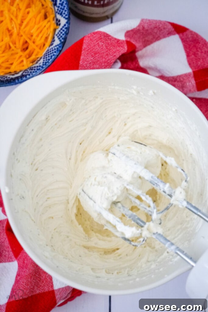 Creamy Ranch Beer Cheese Dip 7 The ingredients in the mixing bowl are being blended together until smooth and well combined using an electric handheld mixer.