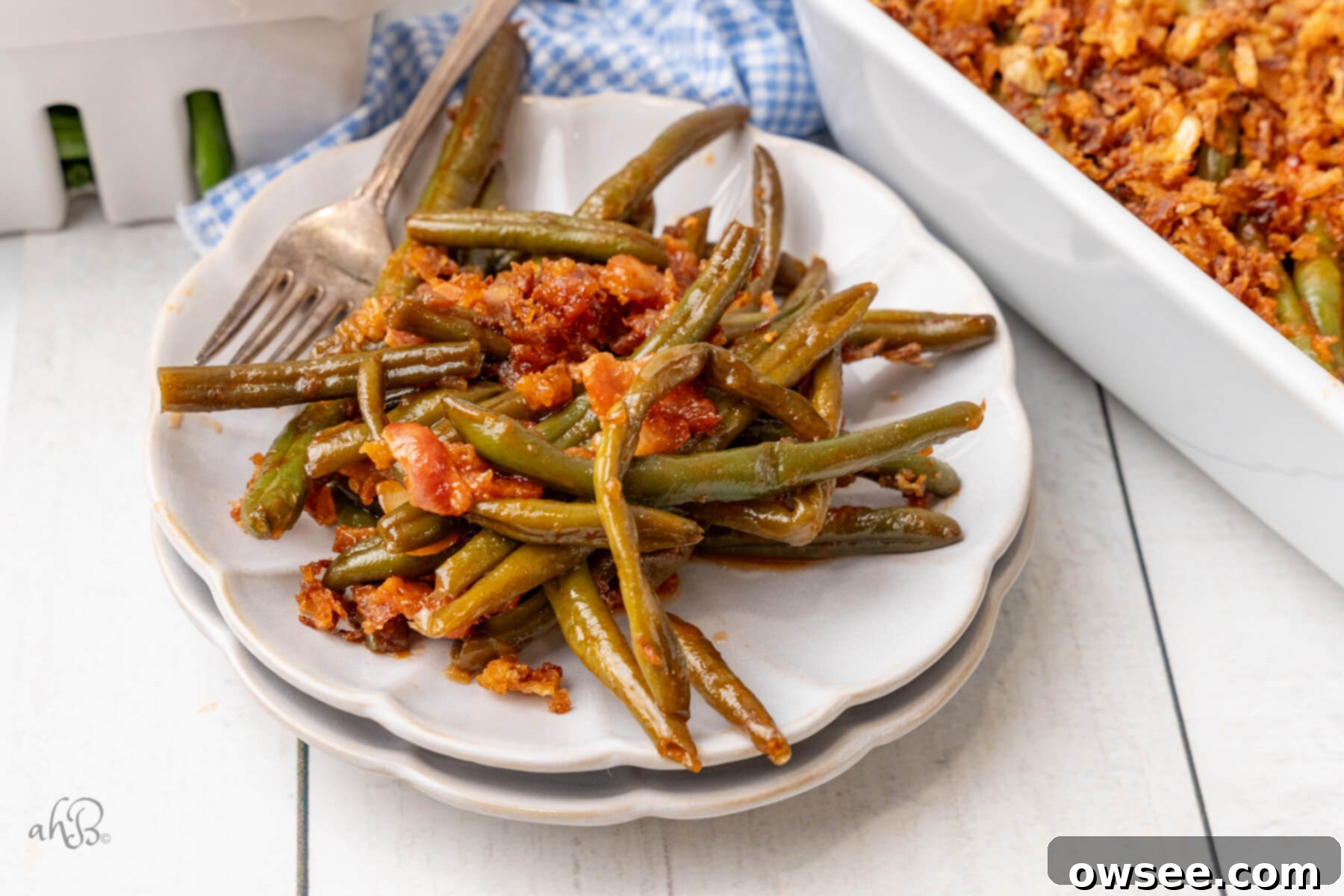 Smoky BBQ Green Bean Casserole 11 Delicious BBQ Green Bean Casserole topped with crispy French fried onions in a white baking dish.