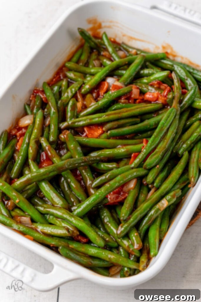 Smoky BBQ Green Bean Casserole 9 Green Beans and crispy bacon pieces are added to the BBQ mixture in the skillet and stirred to coat evenly, preparing for the casserole dish.