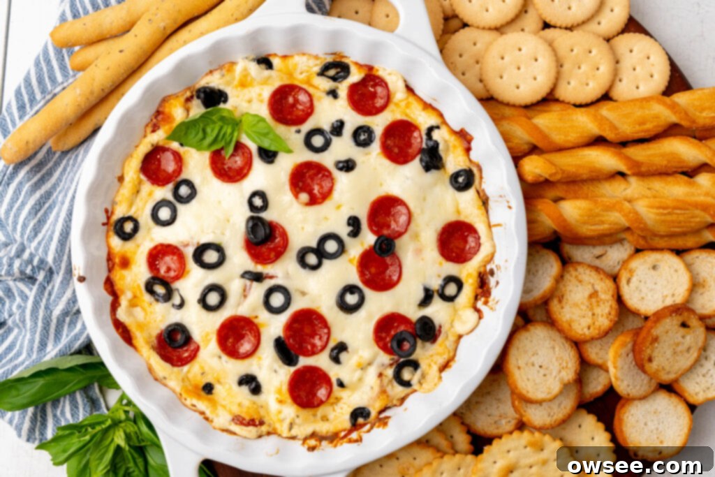 Hot Cheesy Pepperoni Dip 3 A serving tray laden with a variety of dippers, including crackers, breadsticks, and toast rounds, arranged beautifully around a bowl of Cheesy Pepperoni Pizza Dip, ready for a party.