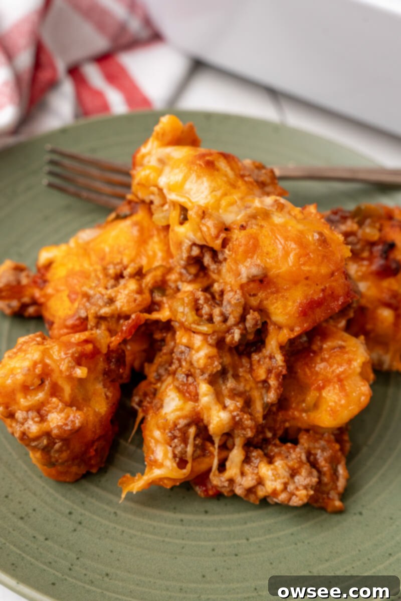 A generous serving of sloppy joe biscuit casserole on a vibrant green plate, showcasing its golden-brown biscuits and rich filling.
