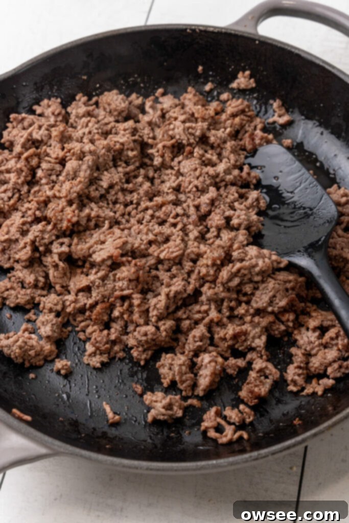 Ground beef being browned in a large skillet over medium heat.