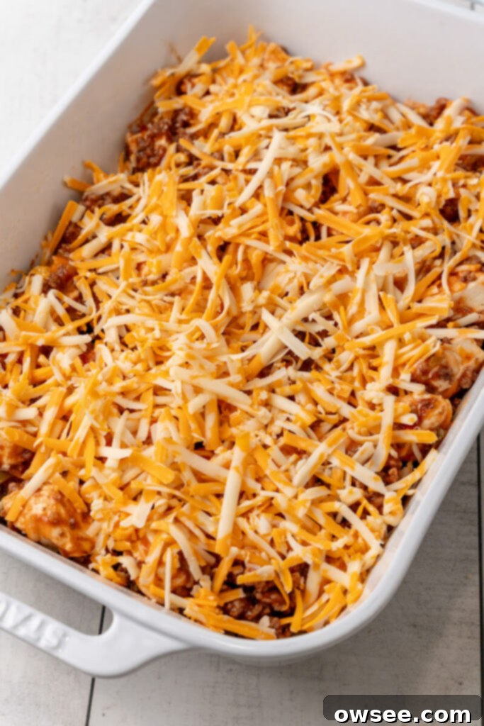 The sloppy joe and biscuit mixture is added to a 9x13 casserole dish and topped with the remaining shredded cheese.