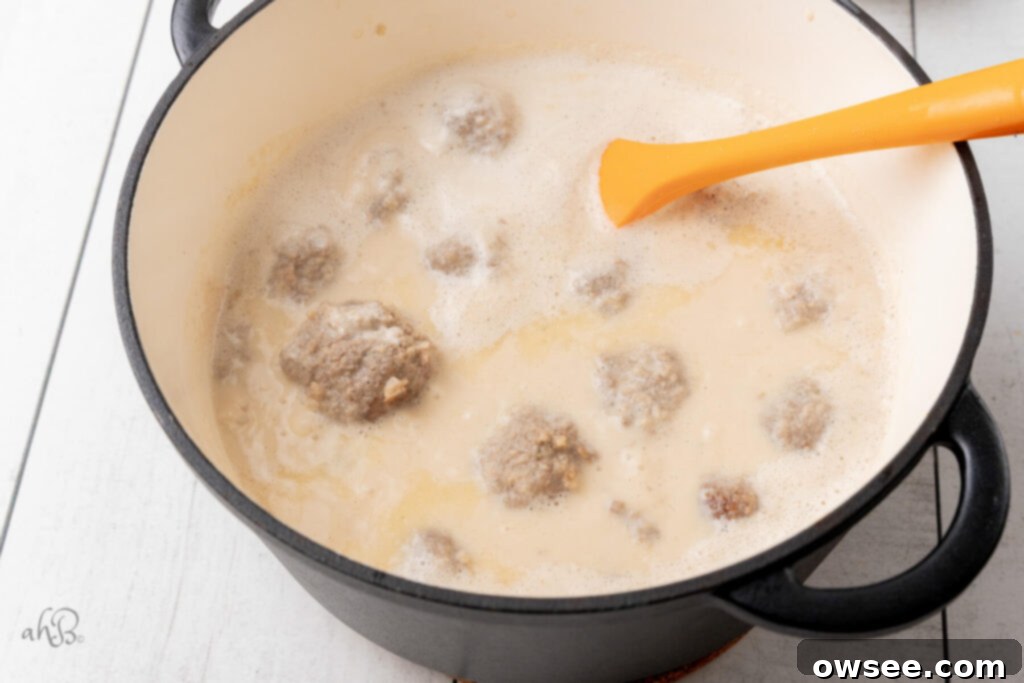 Creamy One Pot Swedish Meatballs and Noodles 7 A Dutch oven full of the Swedish meatballs after browning, with the ingredients for the gravy added.