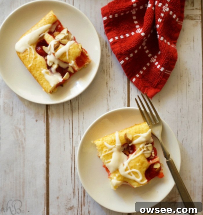 A sheet pan of Cherry Almond Squares cooling on a wire rack, topped with cherries and sliced almonds, awaiting the final glaze.