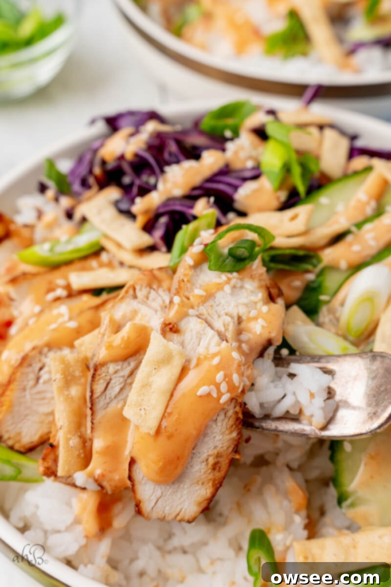 Bold Bang Bang Chicken Bowls 3 A piece of chicken is taken from the bowl with a fork, showing the texture of the cooked chicken.