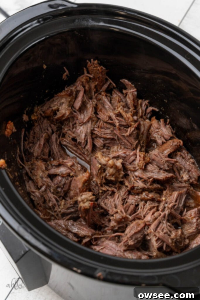The incredibly tender roast is easily shredded directly in the crockpot using two forks, allowing it to absorb more of the rich cooking liquid.