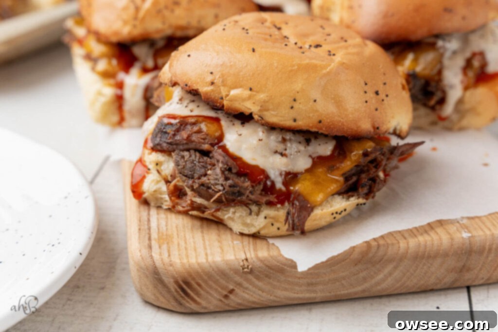 The complete beef 'n cheddar sandwiches, beautifully assembled and ready to eat, are artfully arranged on a rustic wooden cutting board, inviting you to take a bite.