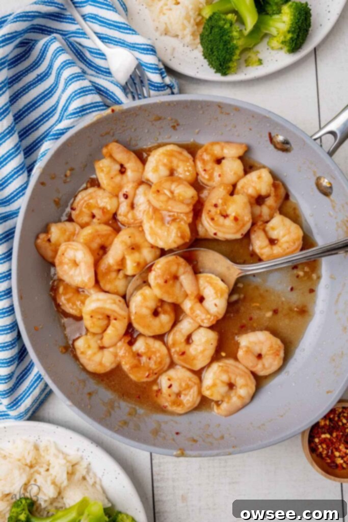 Honey Garlic Glazed Shrimp 3 A gray nonstick skillet full of sticky honey garlic honey shrimp. 3 shrimp rest in a spoon.