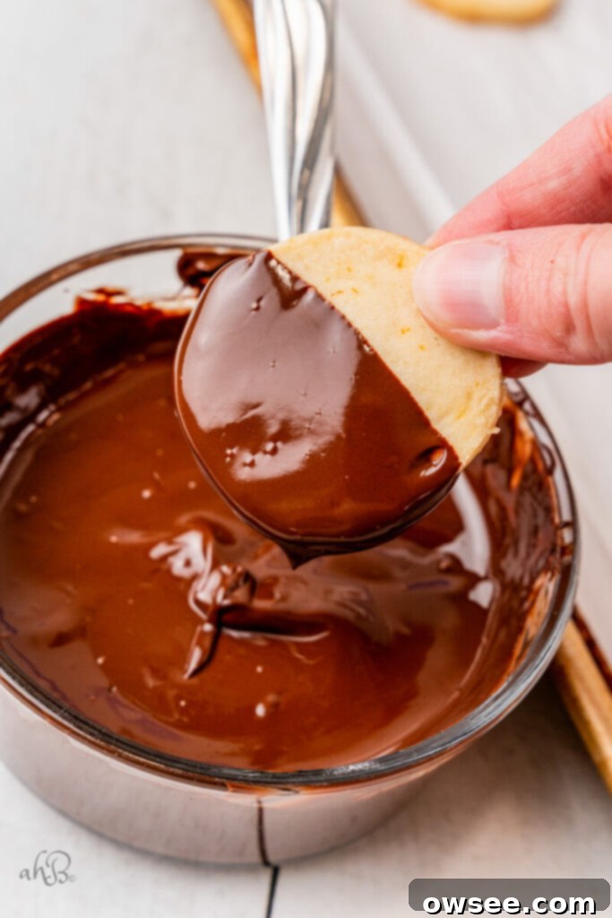Decadent Orange Chocolate Shortbread 12 A shortbread cookie is dipped halfway into a glass bowl of melted chocolate.