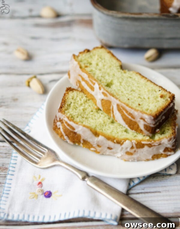 Two generous slices of moist pistachio pudding pound cake on a white plate, ready to be enjoyed