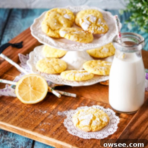 Zesty Lemon Crinkle Cookies 2 A wooden tray holding a plate of lemon crinkle cookies, a glass milk bottle and a sliced lemon.