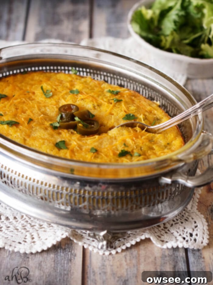 A casserole dish of Mexican Spoon Bread with a spoon in the center of the casserole. 