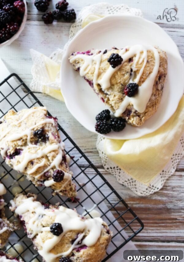 Close-up of a tender and flaky scone studded with sweet tart blackberries and topped with a rich cream cheese glaze.