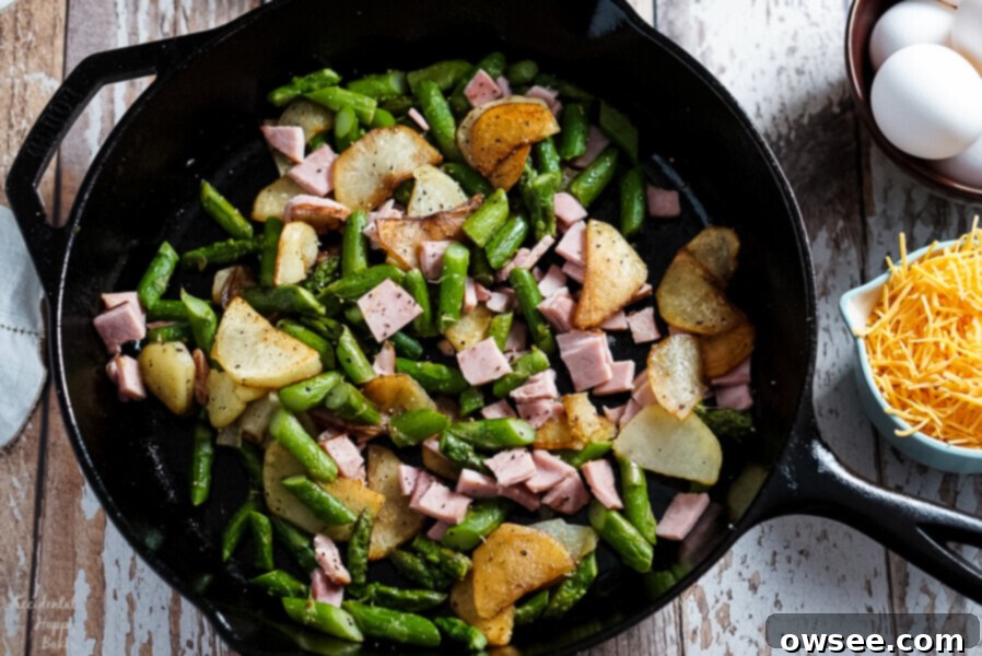 Potatoes, Ham, and Asparagus are cooked in a cast iron skillet before adding the eggs for the frittata. 