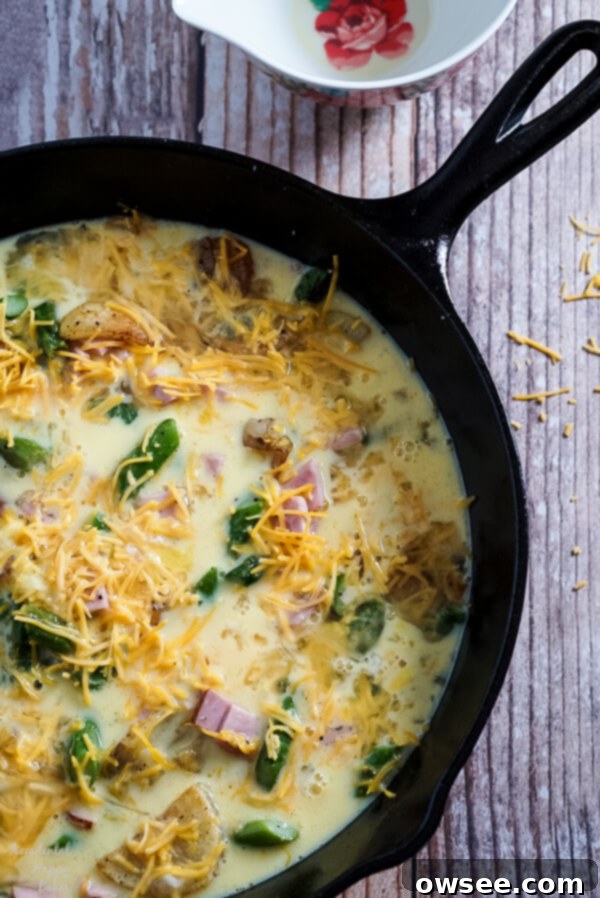 Whisked eggs are added to the cooked vegetables in the cast iron skillet before baking.