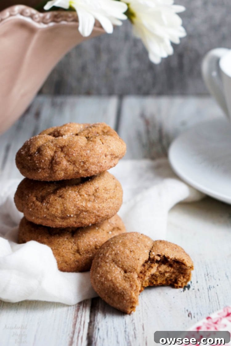 A stack of freshly baked pumpkin gingersnap cookies, showing their soft interiors and appealing crinkled tops.