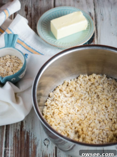 A bowl of old fashioned oats soaking in hot water with melted butter, preparing the base for oatmeal dinner rolls.