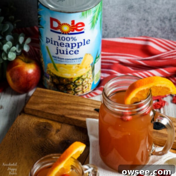 Old Fashioned Wassail served in elegant glass mugs on a wooden tray, garnished with citrus and cinnamon.