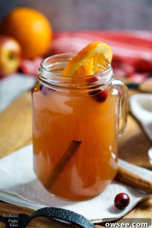 A festive table setting with a large punch bowl of Wassail, garnished with oranges and cinnamon, ready for a holiday gathering.