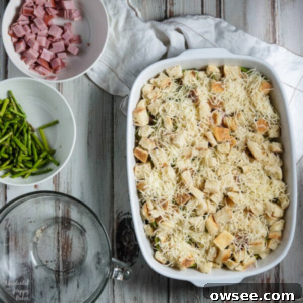 The savory ham and asparagus strata drenched in an egg and Hollandaise mixture, ready to bake for a delicious breakfast.