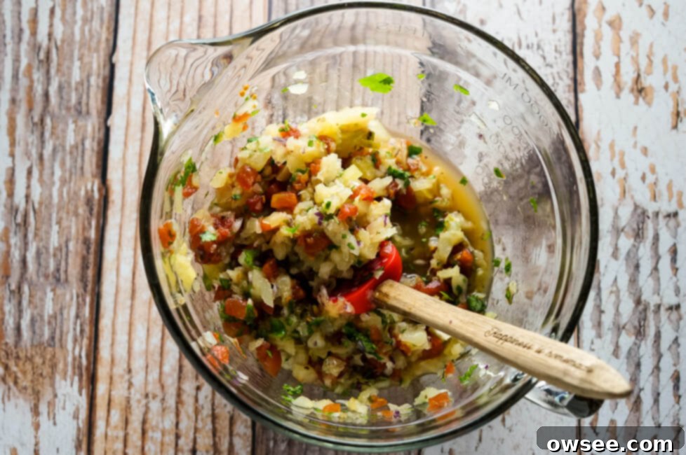 A bowl of pineapple salsa with a serving spoon on a rustic wooden surface.