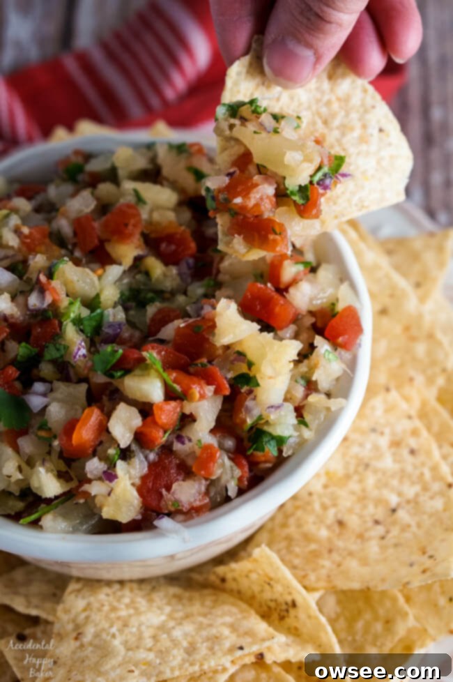 A bowl of easy pineapple salsa with a stack of tortilla chips ready for dipping.