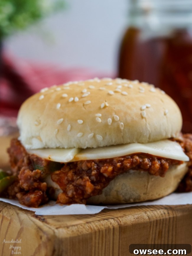 An Italian Sloppy Joe Sandwich sitting on a cutting board, garnished with fresh basil. 
