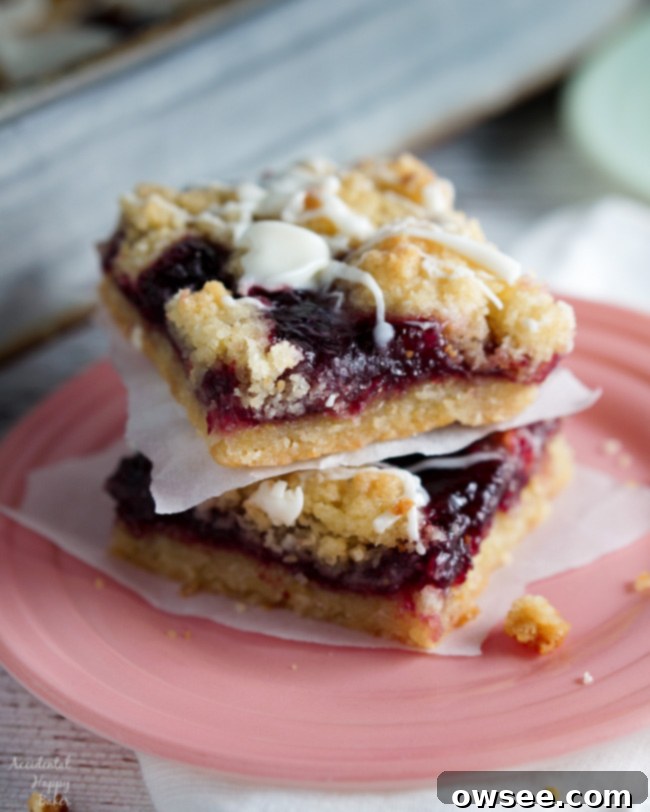 Two Raspberry White Chocolate Shortbread bars sitting on a plate, showcasing their layers of jam and white chocolate.