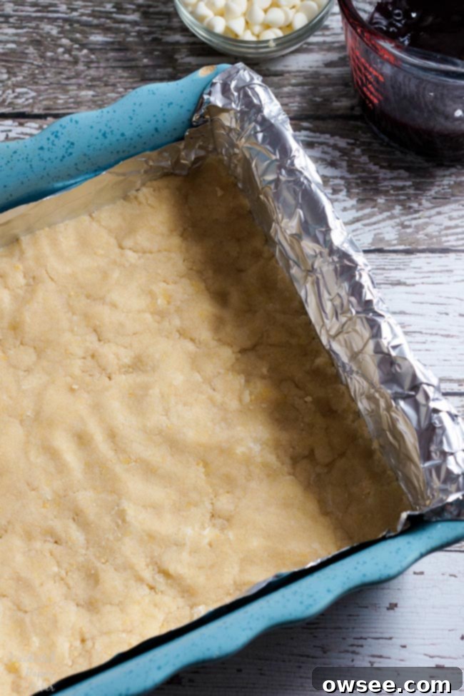 First a layer of crumbly shortbread dough is pressed into a foil lined baking pan.
