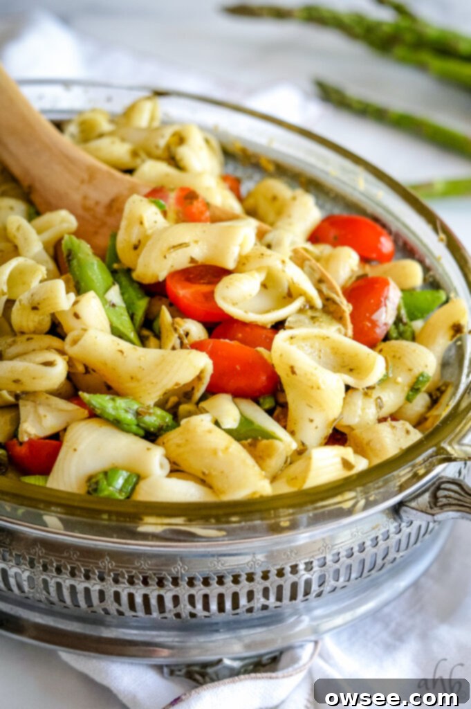 Rich Pesto Pasta Delight 5 Cooked pasta, cherry tomatoes, and asparagus mixed with pesto in a bowl.