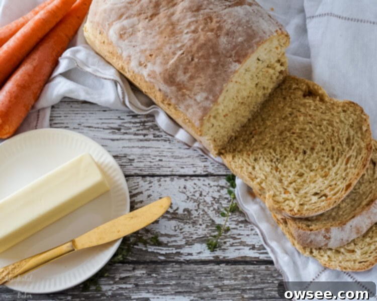 Freshly sliced carrot and chive bread on a cutting board, with a plate of bread and butter in the background.