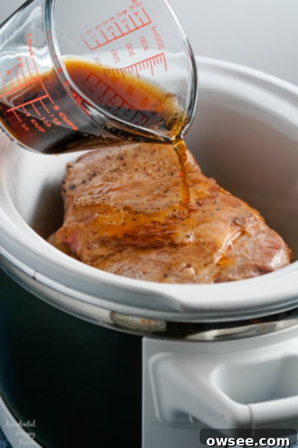 Caramelized Root Beer Pulled Pork 5 A bottle of root beer is poured over the seared pork roast, apples, and onions inside the slow cooker, ready for braising.