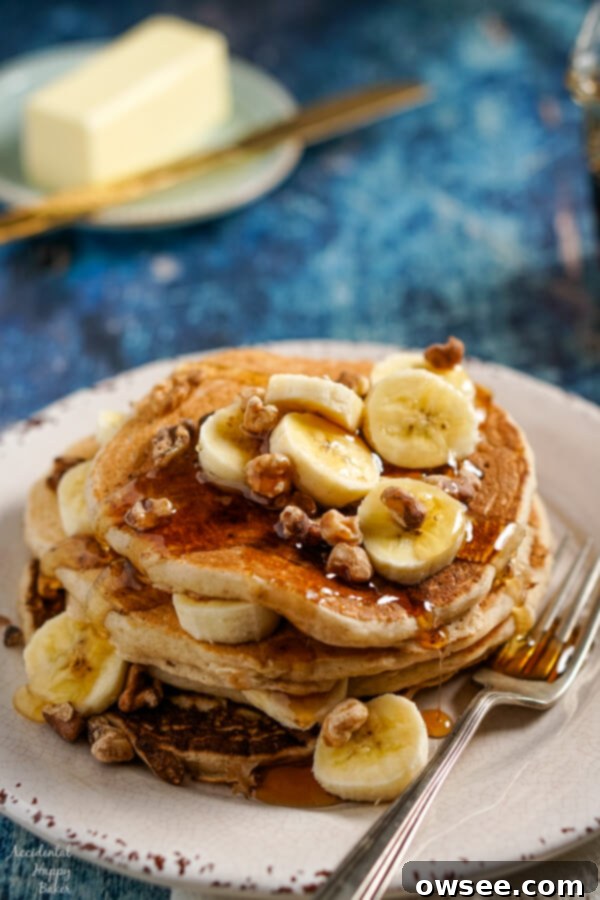 Fluffy Banana Bliss 3 A stack of banana pancakes topped with sliced bananas, toasted walnuts, and maple syrup