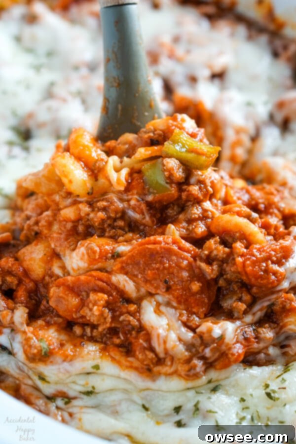 A spoonful of gooey mozzarella cheese, ground beef, Italian sausage, and pepperoni in tomato sauce with pasta.