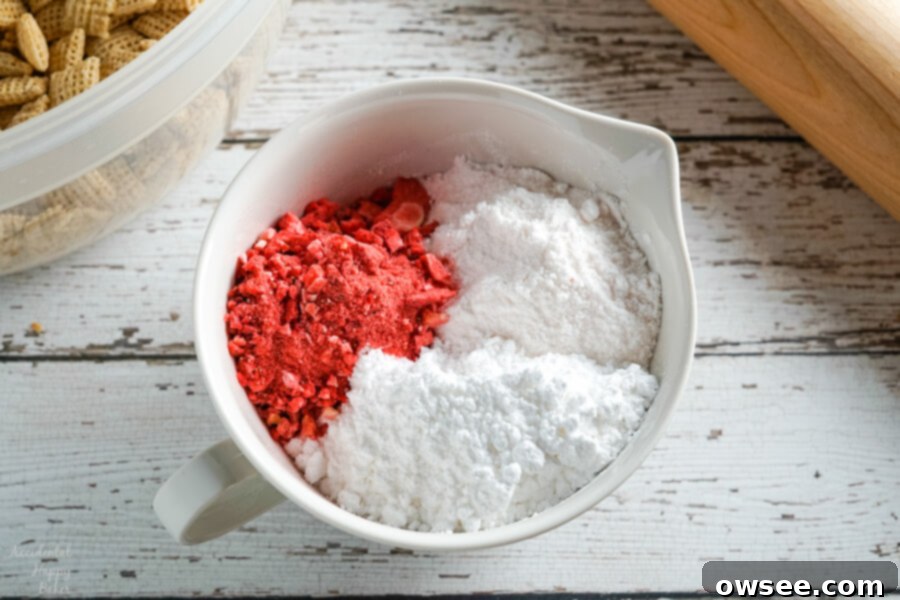 A bowl full of the coating for Strawberry Cheesecake muddy buddies.