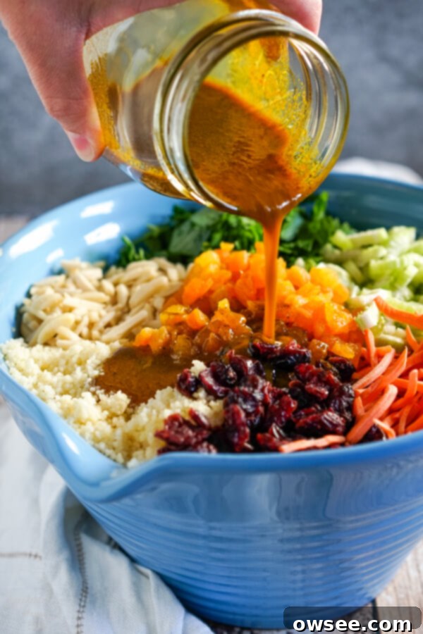 Sunshine Couscous Salad 5 The golden curry dressing is poured over the top of the colorful curried couscous salad ingredients in a bowl.