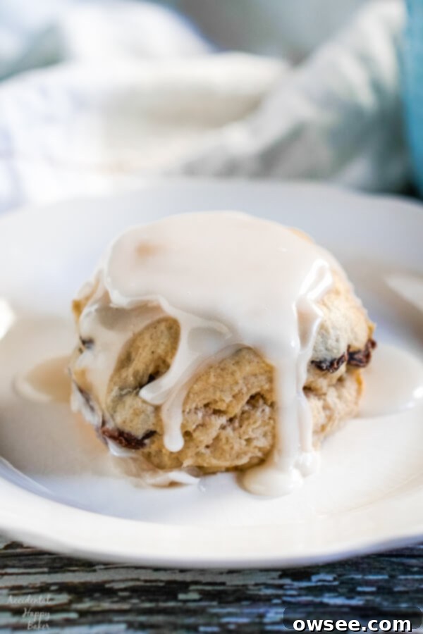 A cinnamon raisin biscuit, covered with creamy vanilla glaze on a white plate. This is a Hardee's copycat recipe.