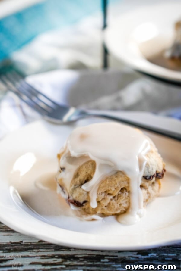 Homestyle Cinnamon Raisin Biscuits 4 A stack of two glazed cinnamon raisin biscuits on a white plate, showcasing the fluffy texture and plump raisins.