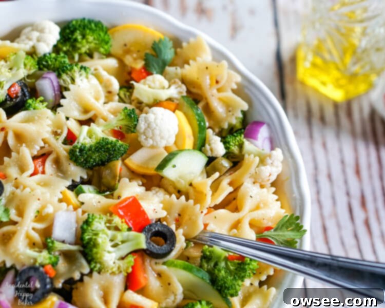 Bright Summer Pasta Delight 2 Summer vegetables and farfelle pasta tossed with an Italian dressing in a white bowl.