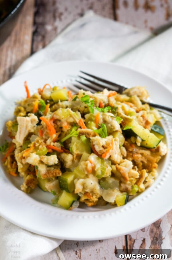 Hearty Chicken Zucchini Delight 7 A white plate with a serving of Chicken Zucchini Casserole sits on top of a cloth napkin on a table.