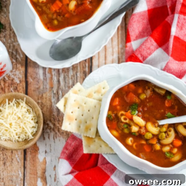 A close-up of a rustic bowl of Hamburger Macaroni Soup, showcasing the rich broth, pasta, beef, and vegetables.