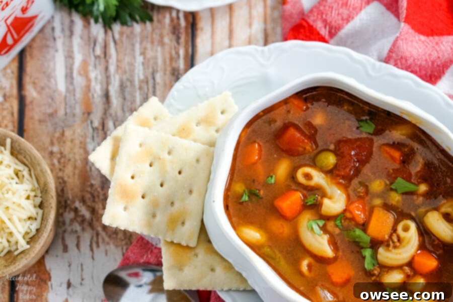 A generous serving of Hamburger Macaroni Soup with a side of golden cornbread, ready for a comforting meal.