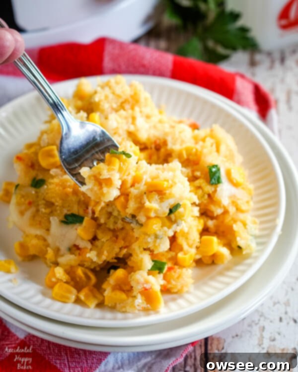 One-Pot Wonder Corn Casserole 7 A serving of crockpot corn casserole on a white plate sitting next to a slow cooker.
