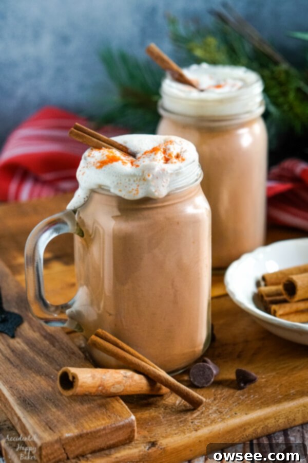 Two mugs of slow cooker Mexican hot cocoa on a serving tray with cinnamon sticks and a sprinkle of cayenne.